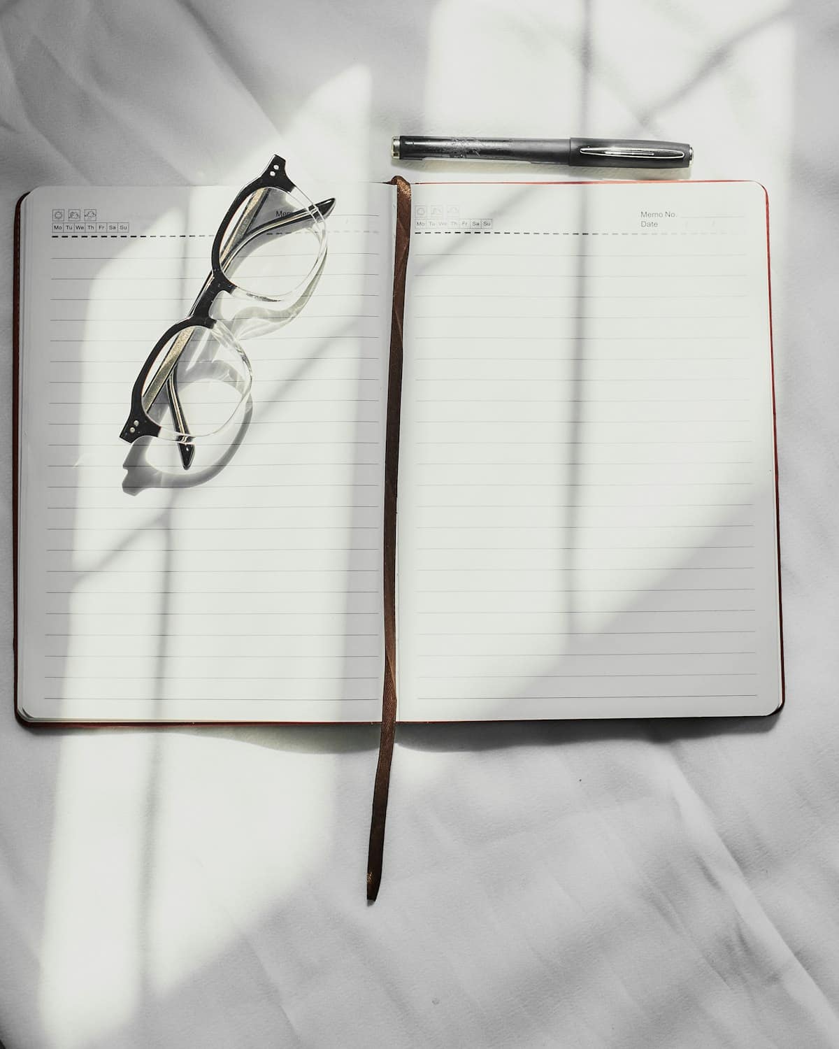 A clean professional notebook with a pen, eyeglasses, and document design tools