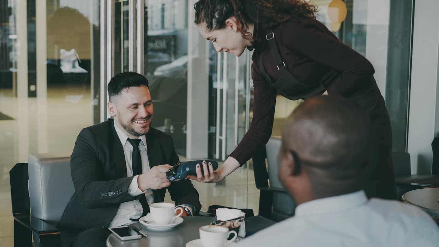 A customer paying by card at a restaurant table