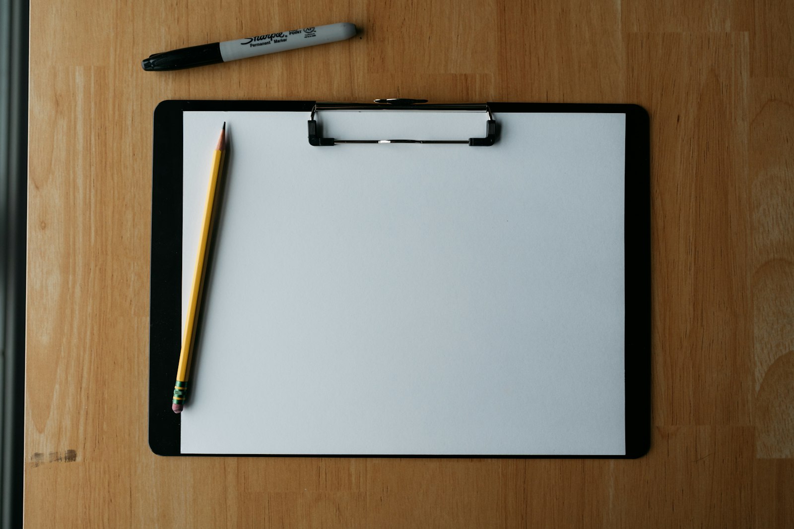 A clipboard, pencil and pen on a desk