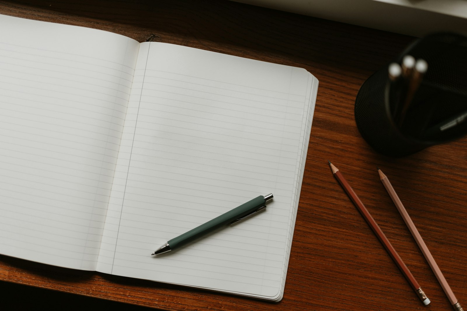 An open notebook with a pen and pencils